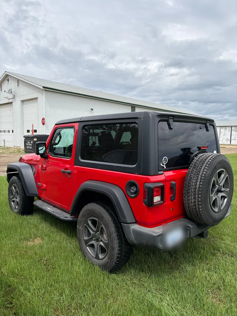 Finished red Jeep Wrangler parked outside the shop