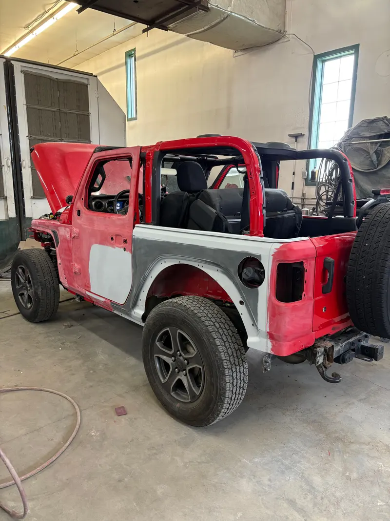 Red Jeep Wrangler in the shop with panels primed for paint