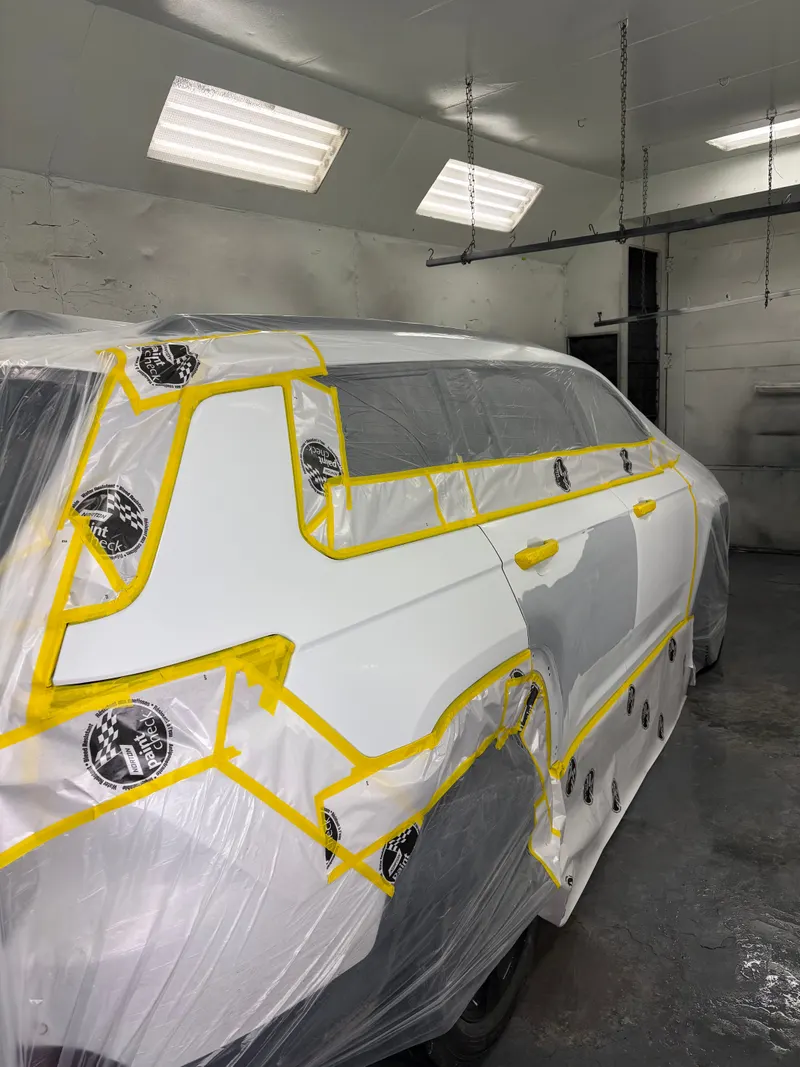 White vehicle masked with yellow tape ready for paint